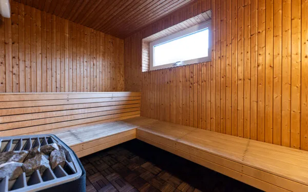 Träinredd bastu med bänk och litet fönster som släpper in dagsljus.