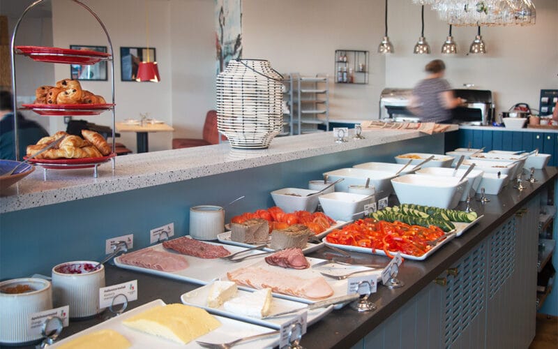 Frukostbuffé med bröd, pålägg, grönsaker och ägg.