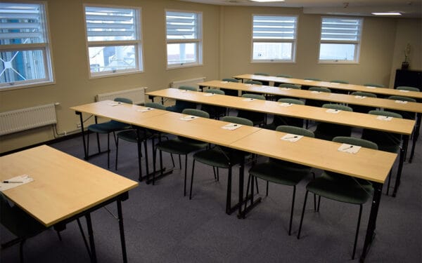 Konferensrum med långbord och stolar framför fönster.