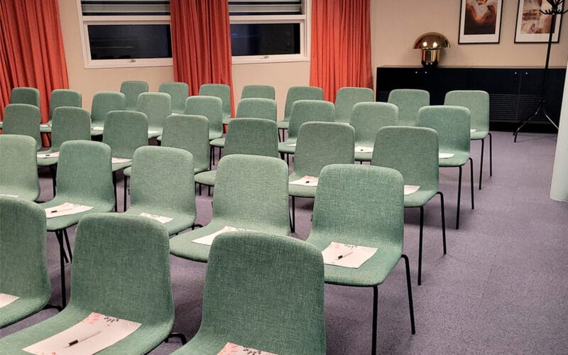 Konferenssal med gröna stolar i biosittning.