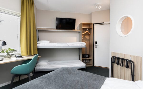 Hotellrum med dubbelsäng och väggfasta våningssängar.