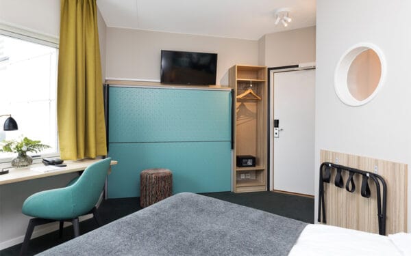 Hotellrum med dubbelsäng, tv och garderob.