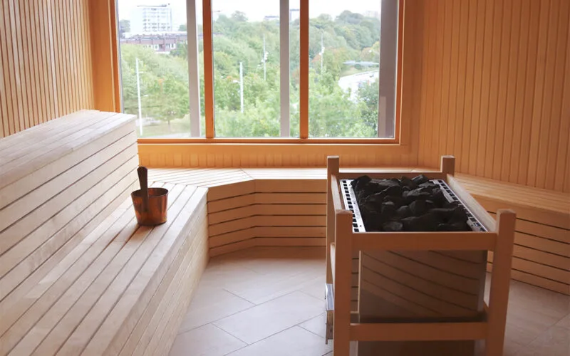 räinredd bastu med bänkar och fönster som släpper in ljus.