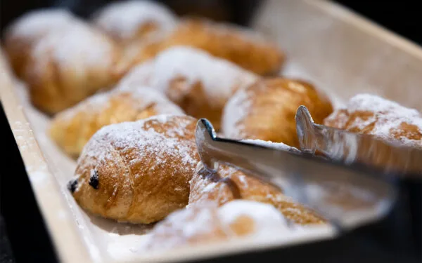 Närbild på nybakade bullar med florsocker på frukostbuffé.