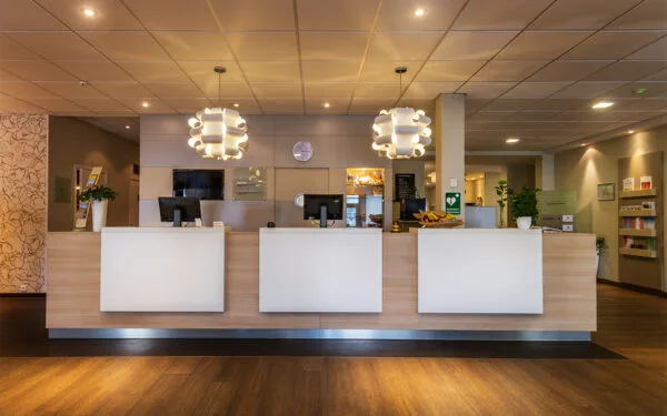 Reception med tre servicediskar och belysning ovanför.