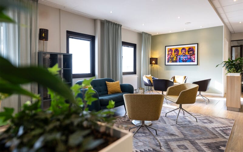 Lounge med soffor, fåtöljer och konst på väggen.