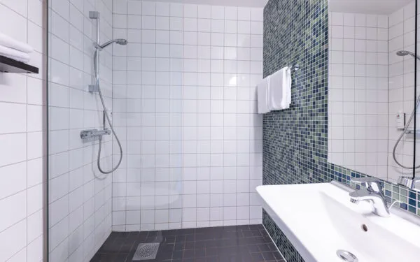 Modernt badrum med duschhörna, handduk och tvättställ.