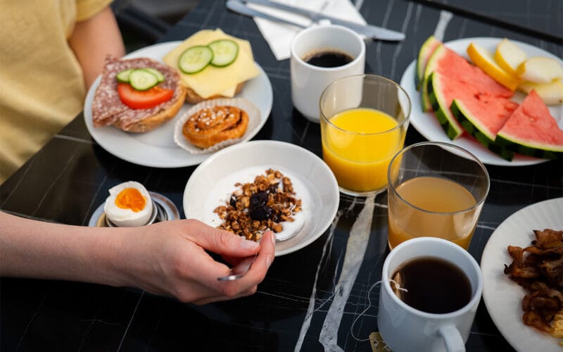 Frukost med smörgåsar, kaffe, juice, melon, ägg och bakverk.