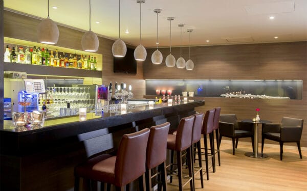 Hotellbar med höga stolar och modern belysning.