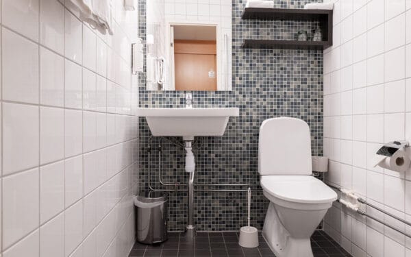 Badrum med toalett, handfat och kaklade väggar.