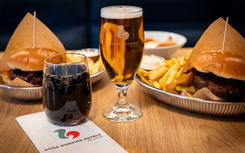 Måltid med pommes frites, dryck och ölglas på restaurangbord.