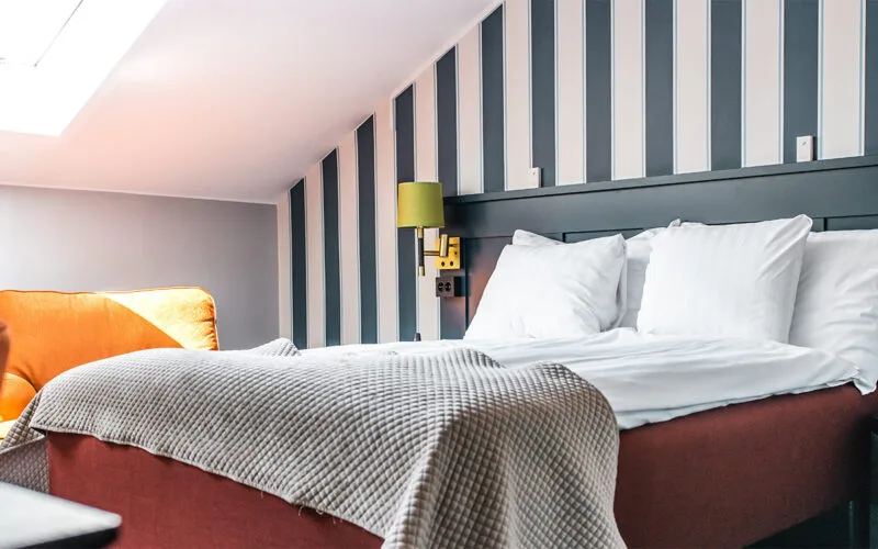 Ljust hotellrum med dubbelsäng och randig fondvägg