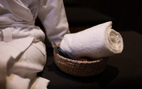 Korg med vit badrock och hoprullad handduk