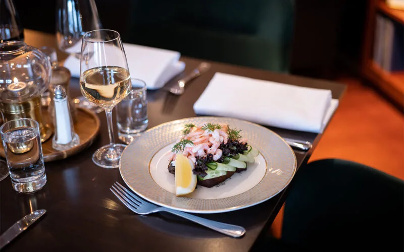 Tallrik med sallad, rökt fisk och glas vin på Restaurang Statt.