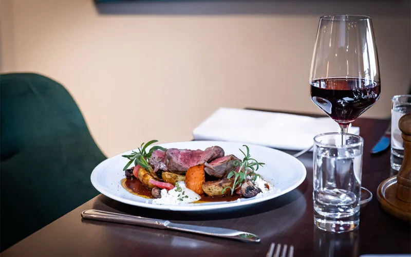 Tallrik med kött, potatis och grönsaker serverad med vin på Restaurang Statt.