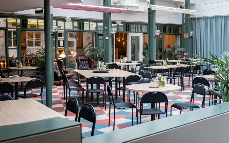 Frukost matsal men stora takfönster, bord och stolar.