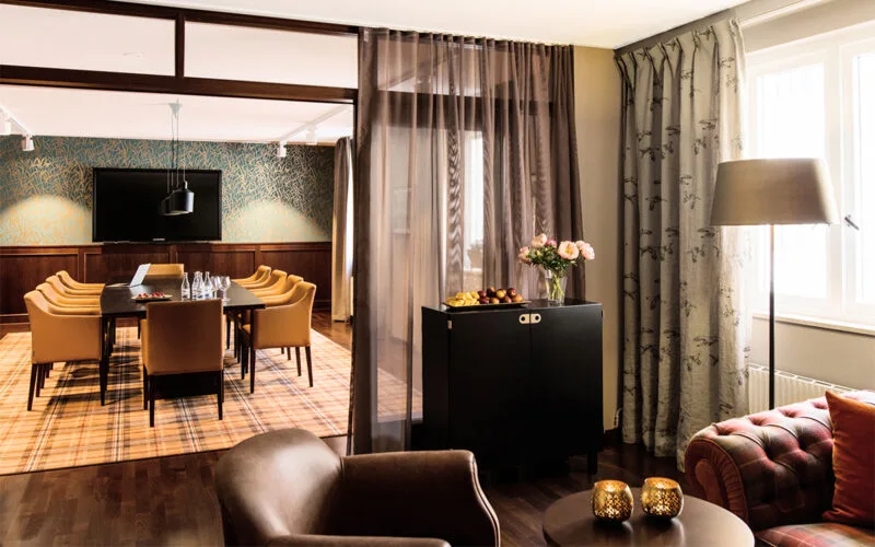 Mötesrum med eleganta skinnfåtöljer och stora fönster.