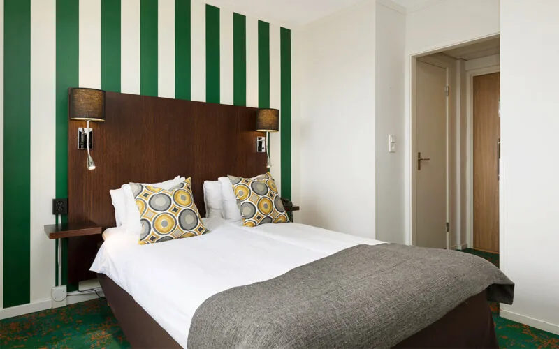 Dubbelrum med vit bäddning, grå filt och randig fondvägg