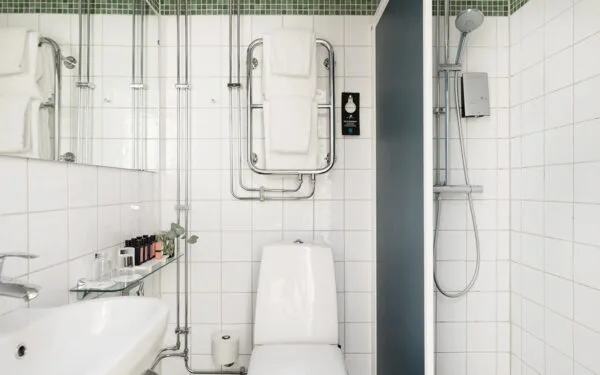 Badrum med dusch, toalett och vita kakelväggar