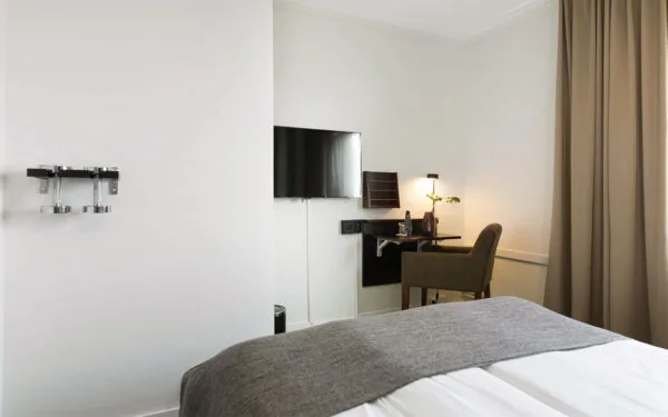 Rum med skrivbord, stol och väggmonterad TV.