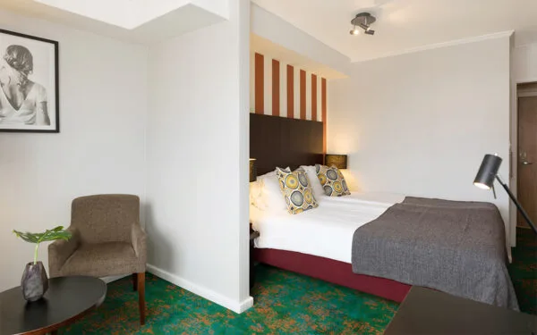 Dubbelrum med vit bäddning, grå filt och heltäckningsmatta