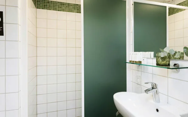 Badrum med dusch, handfat och vita kakelväggar