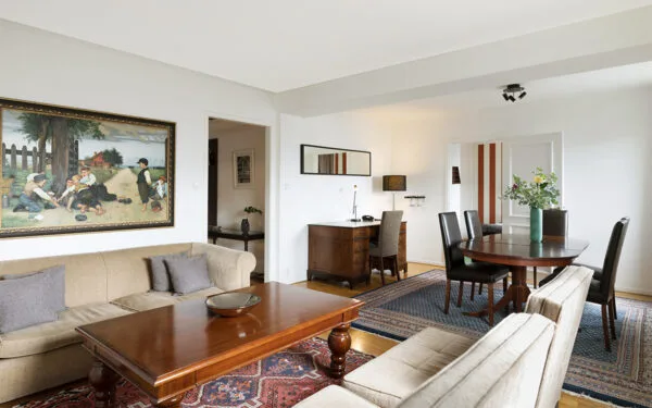 Vardagsrumsdel i hotellsvit med soffgrupp, soffbord, matbord och målning på väggen