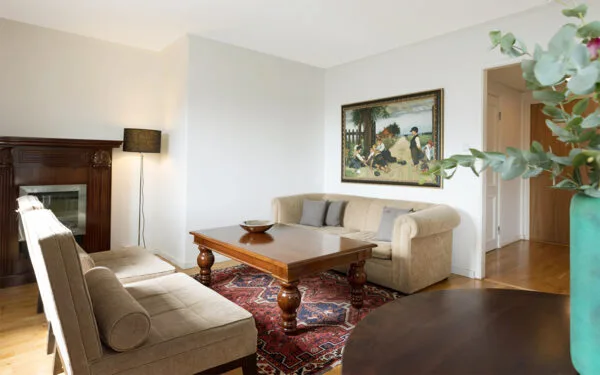 Hotellrum med ljus soffa, soffbord och tavla på väggen, intill ett fönster