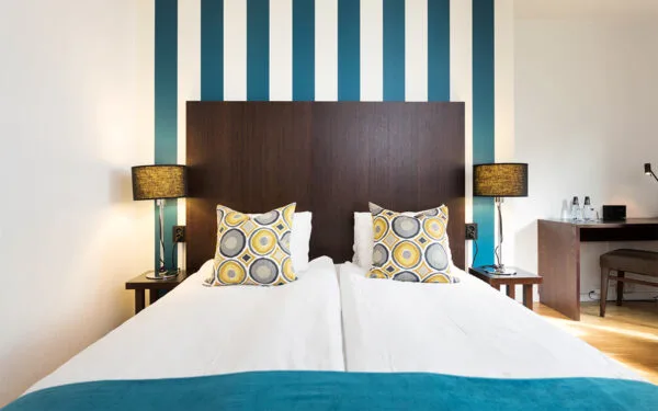 Hotellsäng med randig fondvägg och dekorativa kuddar