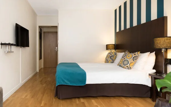 Dubbelrum med vit bäddning, turkost överkast och modern inredning