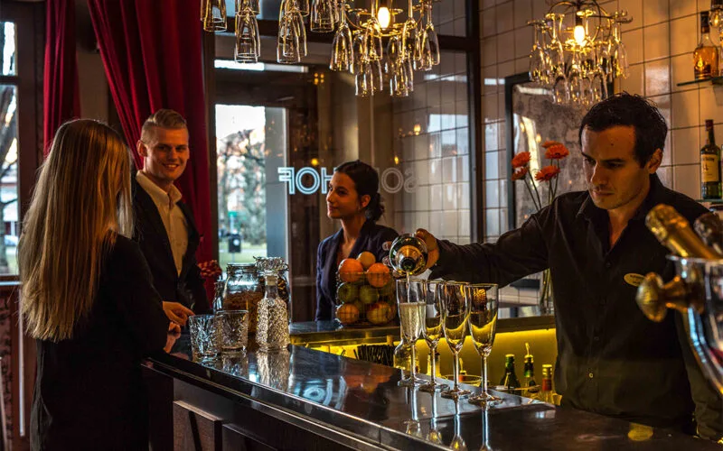 Bartender serverar gäster vid hotellbar med glasdisk.