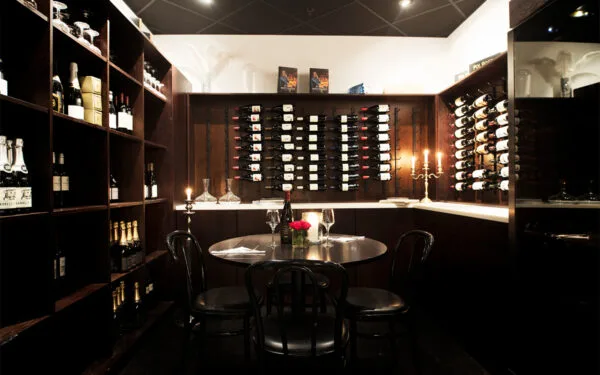 Vinrum med rader av flaskor och dukade bord.