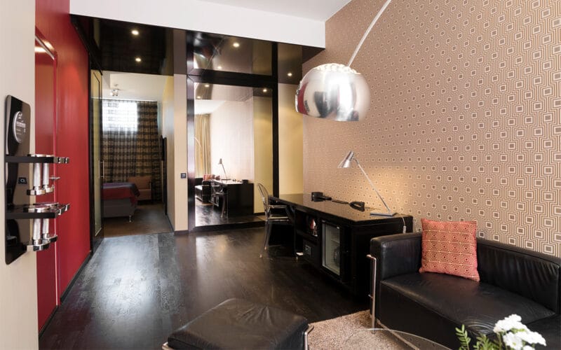 Modernt hotellrum med mörka möbler, skrivbord och speglar.