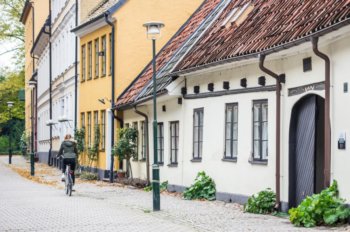 Bild på en gata i Malmö med färgglada hus och en person som cyklar förbi.