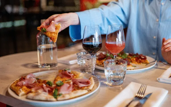 Gäst som tar pizza vid bord på restaurang Angelini