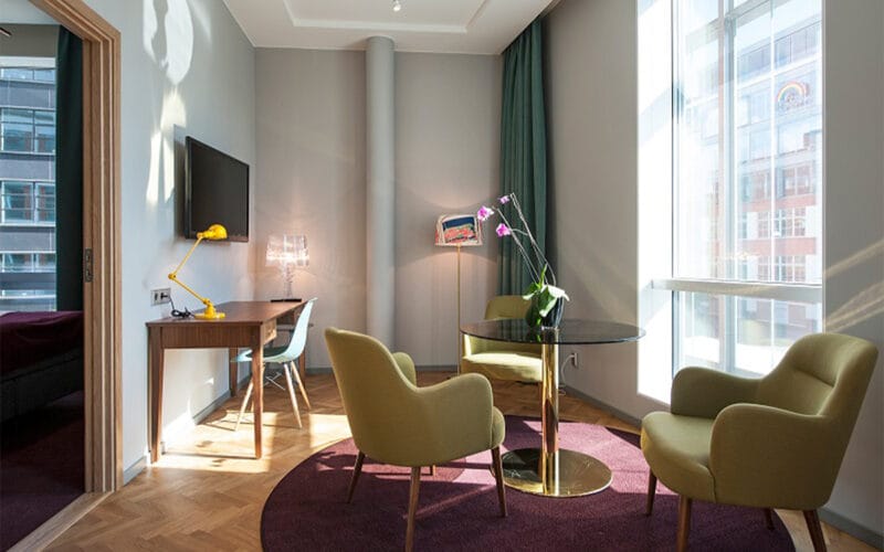 Sittgrupp med runda bord, fåtöljer, orkidé och skrivbord med gul lampa.