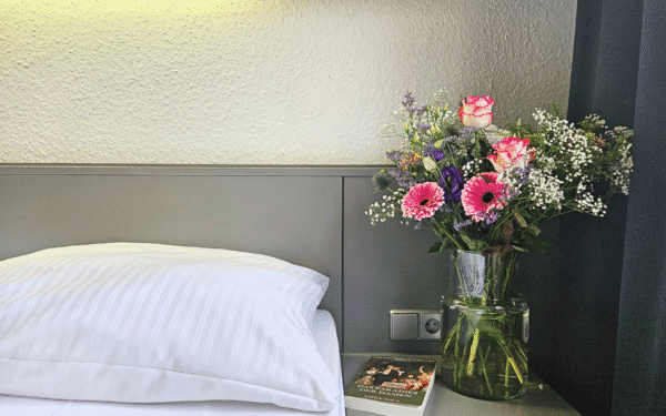 Kopfkissen mit Blumen auf dem Nachtstand und ein Buch.