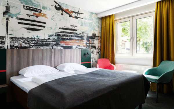 Doppelzimmer mit einem Doppelbett, Sitzgelegenheit und Gardinen