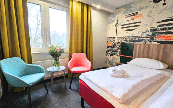 Modern eingerichtetes Hotelzimmer mit Doppelbett, einem Tisch, zwei Stühle und grüne Gardienen