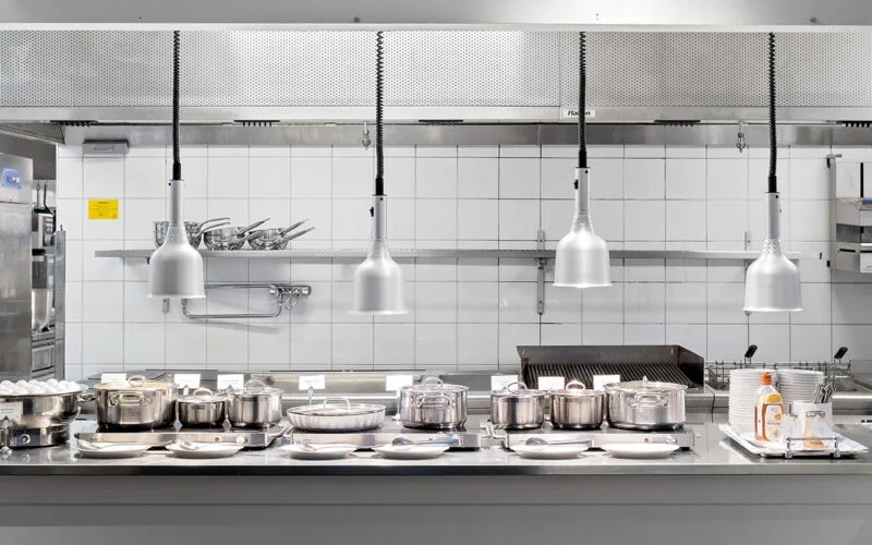 Bufféservering med kastruller, fat och tallrikar under lampor i restaurangkök.