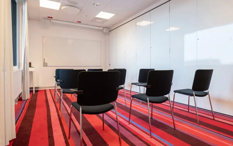 Litet mötesrum med biosittning och whiteboard.