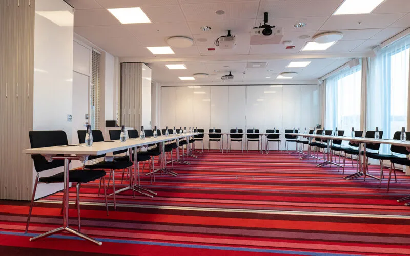 Stort mötesrum med U-formade bord och stolar.
