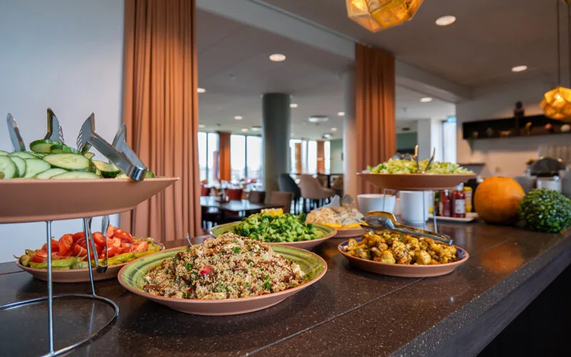 Buffé med sallader, grönsaker och varma rätter uppdukade på ett serveringsbord.