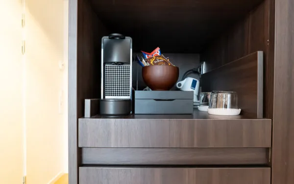 Kaffestation med espressomaskin, tekokare, muggar och tepåsar.