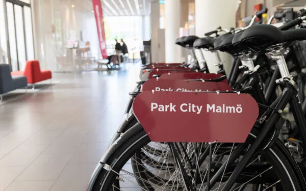 Rader av svarta cyklar med skylten ”Park City Malmö” i en ljus, modern lobby.