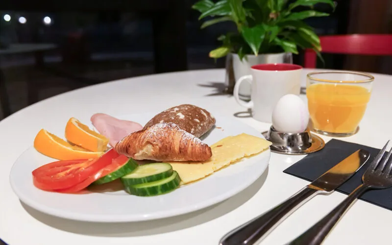 Frukost med bröd, croissant, ost, skinka, grönsaker, kokt ägg och juice.