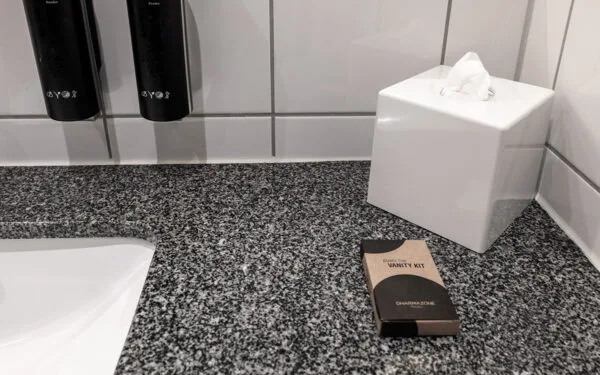 Badrumsyta med granitbänk, pappershållare i vitt porslin och ett vanity kit.