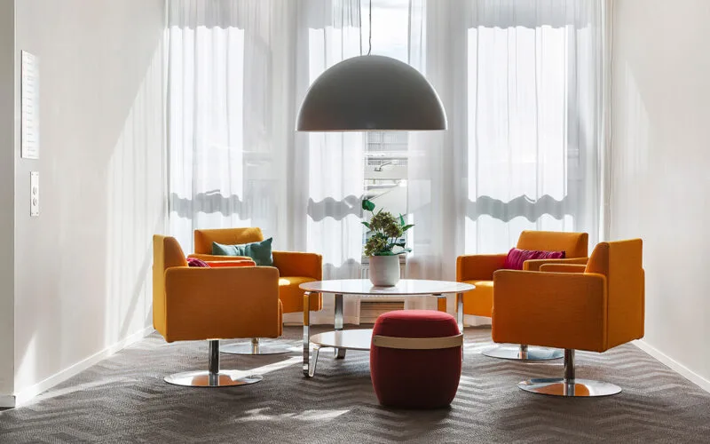 Sittgrupp med färgglada fåtöljer och soffbord i ljus lobby.