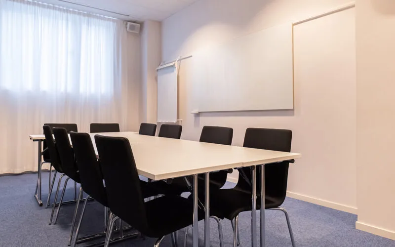 Konferensrum med mötesbord, stolar och whiteboard.