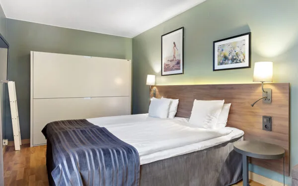 Bekvämt hotellrum med dubbelsäng, stilfull inredning och smart uppfälld extrasäng för extra sovplatser.